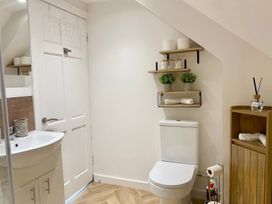 A bathroom with a toilet and sink along with shelves for towels and decor at Central Tenby 3 Bed Apt Sleeps 6 to 8 Dog Friendly in Tenby