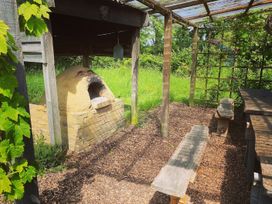 An outdoor area with an oven, wooden benches, and a table at Pet Friendly 3Bed Barn Sleeps 7 Parking Garden in Westhall near Halesworth