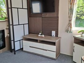 A media console with a television and decorative plants at Homely Caravan in Skegness