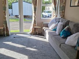 A living room with a sofa and curtains at Homely Caravan in Skegness