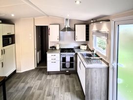 A kitchen with a stove, sink, and cabinets at Homely Caravan in Skegness