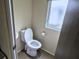A bathroom with a toilet and sink at Homely Caravan in Skegness