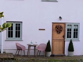 An outdoor seating area with a table and chairs at Yr Hen Beudy Barn Conversion Sleeps 4 Dogs Ok, Brodle Farm near Llansteffan