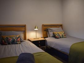 A bedroom with two beds and a lamp at Yr Hen Beudy Barn Conversion Sleeps 4 Dogs Ok near Brodle Farm near Llansteffan