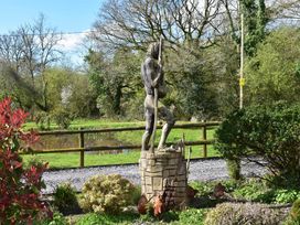 A statue in a garden with trees and a pond at Yr Hen Beudy Barn Conversion Sleeps 4 Dogs Ok in Broadle Farm near Llansteffan