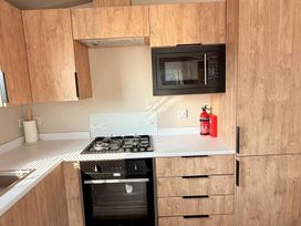 A kitchen with cabinets, stove, microwave and fire extinguisher at 3Bed Sleeps 6 Parking Balcony Flamingo Land Resort near Kirkby Misperton