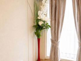 A plant in a red vase and curtains by a window