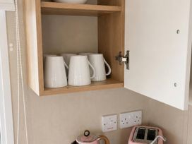 A kitchen with mugs on a shelf and a kettle and toaster on the counter at the property in location