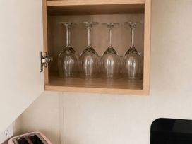 A cupboard with glasses and a toaster in the kitchen