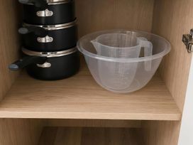 A kitchen cabinet with stacked pans and a measuring bowl