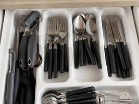 A drawer containing forks, spoons, knives, and kitchen utensils in a kitchen
