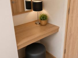 A dressing area with a desk, lamp, and plant near a mirror at a property in unspecified location