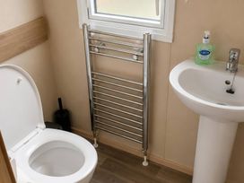 A bathroom with a toilet, sink, and towel rail at 