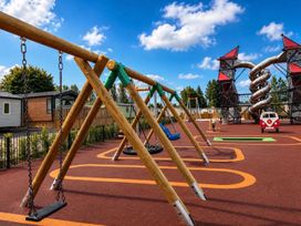 A playground with swings and a climbing structure at Lillardsedge Luxury Caravan Sleeps 6 with Parking Lilliardsedge Holiday Park near St Boswells