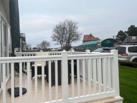 A deck area with furniture and trees at Surfside Bliss Cayton Bay Park caravan Cayton Bay