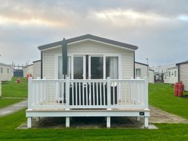 A caravan with a deck in a grassy area at Surfside Bliss Cayton Bay Park caravan, Cayton Bay