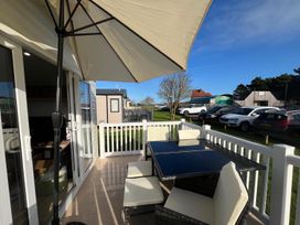 An outdoor seating area with a table and chairs at Surfside Bliss Cayton Bay Park caravan in Cayton Bay