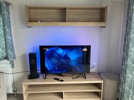 A living room with a television and an entertainment unit at Surfside Bliss Cayton Bay Park caravan