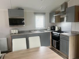 A kitchen with appliances and dining area at Surfside Bliss Cayton Bay Park caravan