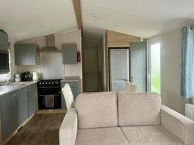 A kitchen with a refrigerator, oven, and sink at Surfside Bliss Cayton Bay Park caravan in Cayton Bay