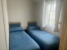 A bedroom with two single beds at Surfside Bliss Cayton Bay Park caravan in Cayton Bay