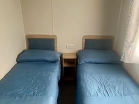 A bedroom with two beds and a nightstand at Surfside Bliss Cayton Bay Park caravan in Cayton Bay