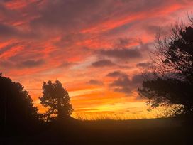 A scenic sunset with trees silhouetted against the sky at Surfside Bliss Cayton Bay Park caravan Cayton Bay