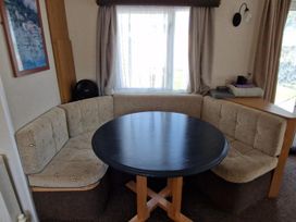 A dining area with a round table and seating at Woodland View Dog Friendly Nr Sutton on Sea, Thurlby near Alford