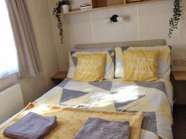 A bedroom featuring a bed with pillows and a shelf at Woodland View Dog Friendly Nr Sutton on Sea Thurlby near Alford