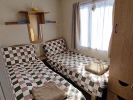 A bedroom with two beds and a shelf at Woodland View Dog Friendly Nr Sutton on Sea Thurlby near Alford