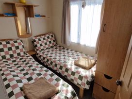 A bedroom with twin beds and a wardrobe at Woodland View Dog Friendly Nr Sutton on Sea Thurlby near Alford