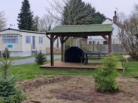An outdoor area with a gazebo, table, and mobile home at Woodland View Dog Friendly Nr Sutton on Sea
