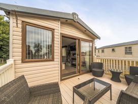 An outdoor area with decking and wicker furniture at The Lodge in Tunstall, North Yorkshire