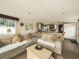 A living room with a sofa and kitchen area at a property in Tunstall, North Yorkshire