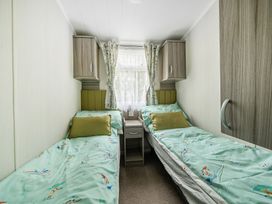 A bedroom with two beds and a window at The Old Barn in Tunstall, North Yorkshire