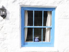 A window with blue frame and curtains at Felin Bach in Aberdaron