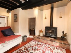 A snug with a stove and sofa at Felin Bach in Aberdaron