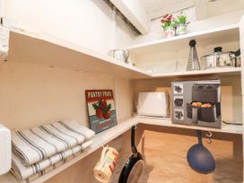 A pantry with shelves containing cooking utensils and appliances at Felin Bach Aberdaron
