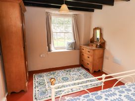 A bedroom with a wardrobe, window, rug, and dresser at Felin Bach in Aberdaron