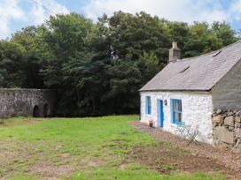 A cottage with a table and chair near a stone bridge at Felin Bach Aberdaron