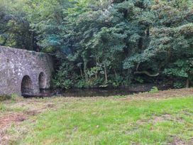 A stone bridge over a stream surrounded by grass and trees at Felin Bach Aberdaron
