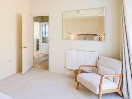 A bedroom with a chair and mirror at 30 Southdown Avenue Weymouth