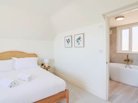 A bedroom with a bed, lamp and doorway to a bathroom at 30 Southdown Avenue, Weymouth
