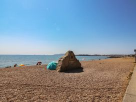A beach with pebbles and umbrellas near the sea at 30 Southdown Avenue Weymouth
