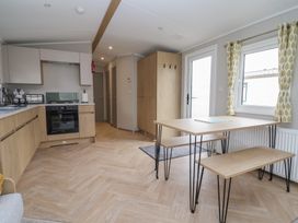 A kitchen with cabinets and a dining table at S7 Abergele