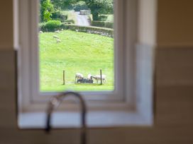 A view of sheep grazing in a field through a window in a kitchen at Bay Bungalow