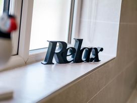 A decorative sign reading Relax on a ledge by a window in the bathroom at Bay Bungalow