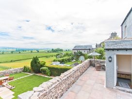 A garden with a stone wall and table with chairs at Hillberry Cottage in Carnforth