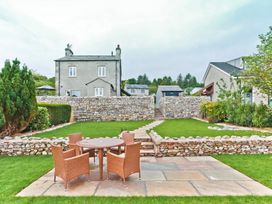 A garden with a stone wall and outdoor seating at Hillberry Cottage in Carnforth