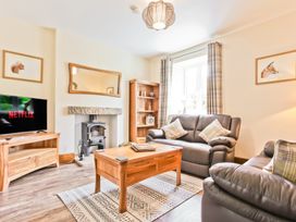 A living room with a television on a stand and a coffee table at Hillberry Cottage in Carnforth